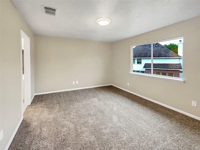carpeted spare room featuring baseboards and visible vents