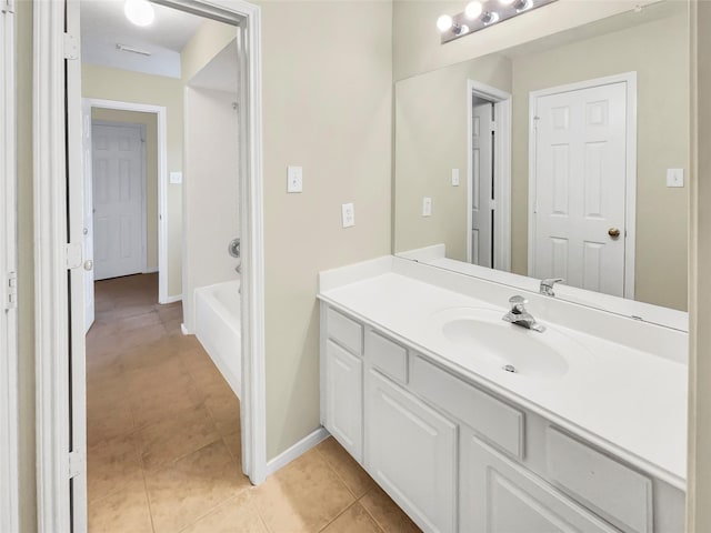 bathroom with tile patterned flooring, baseboards, a washtub, and vanity