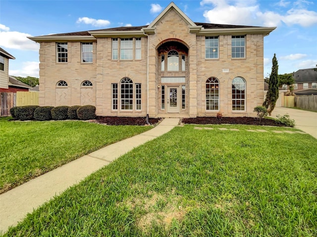 view of front of home with fence, a front lawn, and stone siding