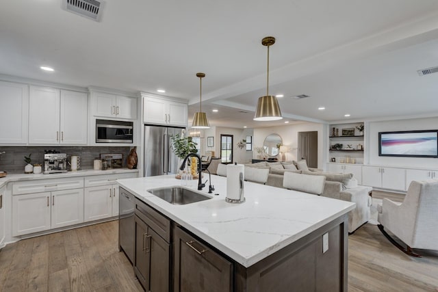 10503 Metronome Dr, Houston, TX 77043 - kitchen with visible vents, white cabinets, a sink, light wood finished floors, and appliances with stainless steel finishes