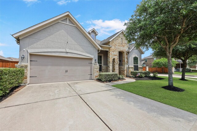 view of front of house with an attached garage, a front lawn, stucco siding, and stone siding
