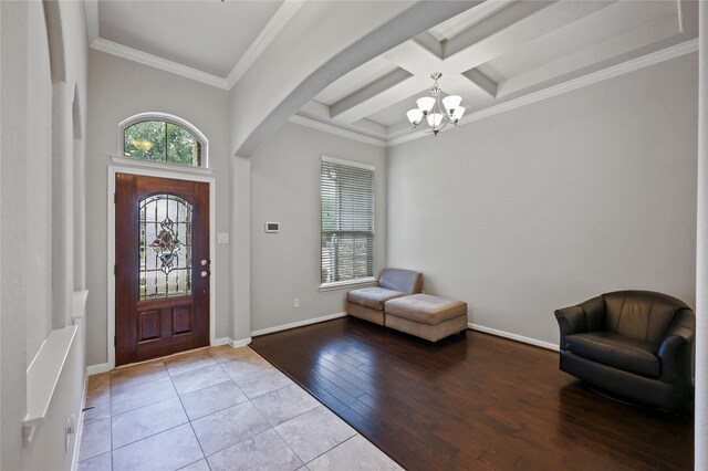 foyer entrance with crown molding, beamed ceiling, arched walkways, coffered ceiling, and a notable chandelier