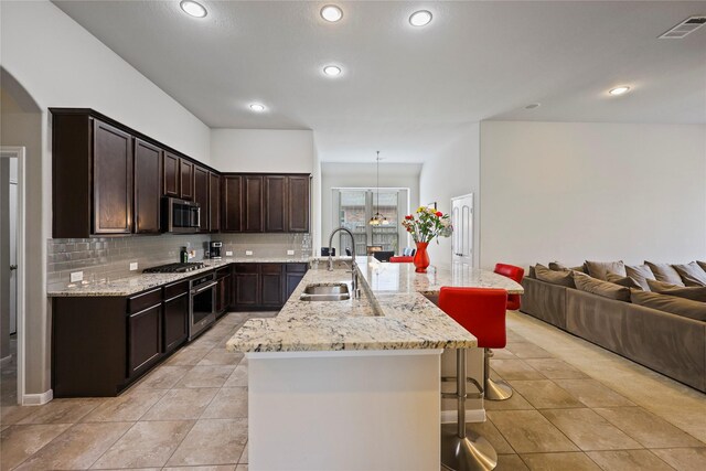 kitchen with visible vents, a breakfast bar, open floor plan, a sink, and appliances with stainless steel finishes