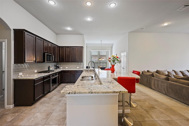 10418 Texas Sage Way, Cypress, TX 77433 - kitchen with stainless steel appliances, a kitchen bar, open floor plan, dark brown cabinets, and tasteful backsplash