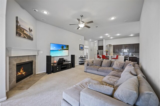 living area with a ceiling fan, light colored carpet, a tiled fireplace, and recessed lighting
