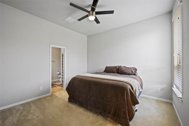 bedroom featuring light colored carpet, baseboards, and ensuite bathroom