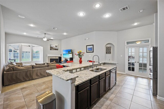 kitchen with a ceiling fan, a lit fireplace, a sink, and dishwasher