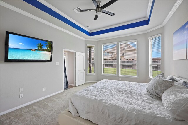 bedroom featuring ceiling fan, carpet floors, baseboards, a tray ceiling, and ornamental molding