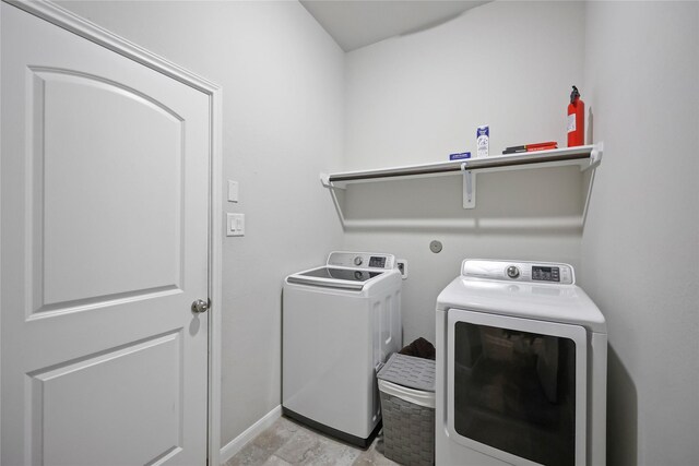 washroom featuring washer and dryer, laundry area, and baseboards