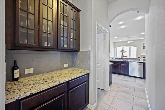 bar with light tile patterned flooring, arched walkways, a ceiling fan, tasteful backsplash, and stainless steel dishwasher