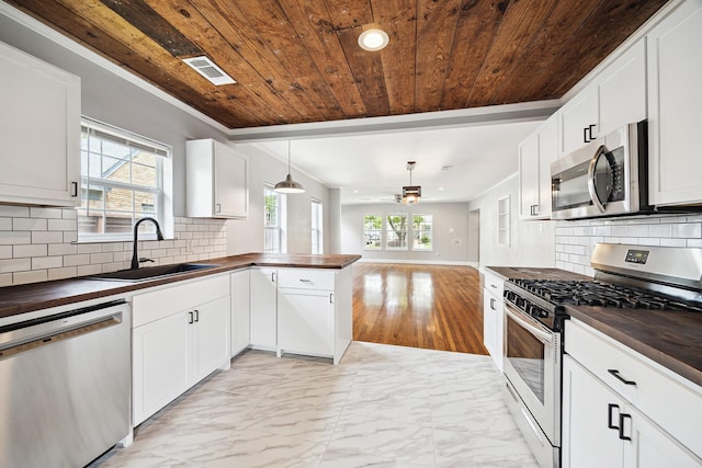 kitchen with stainless steel appliances, a sink, butcher block counters, and wood ceiling