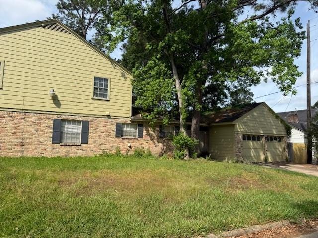 view of side of property with brick siding and a yard