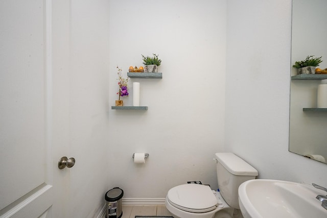 half bath with a sink, baseboards, and toilet