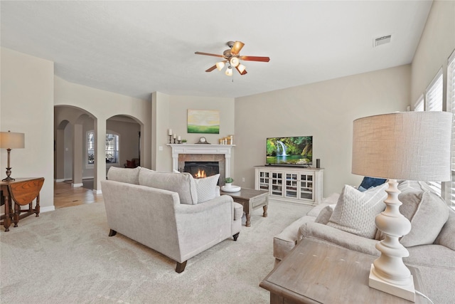 17714 W Copper Lakes Dr, Houston, TX 77095 - living area with ceiling fan, a lit fireplace, light colored carpet, arched walkways, and baseboards