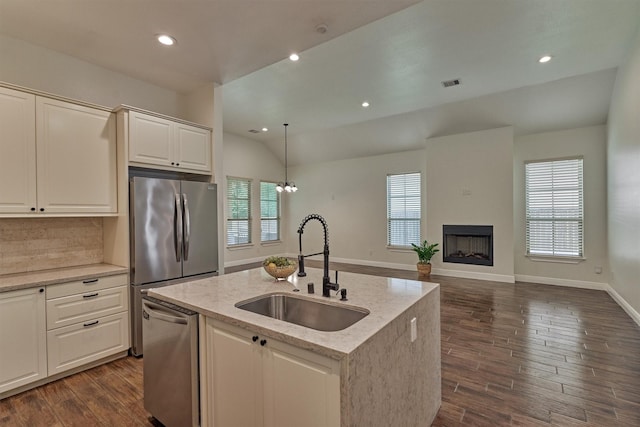 kitchen featuring a sink, light stone counters, stainless steel appliances, and a wealth of natural light