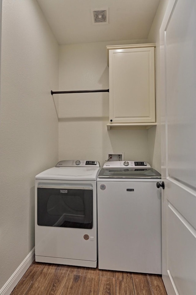washroom with visible vents, cabinet space, baseboards, dark wood-style floors, and washer and dryer