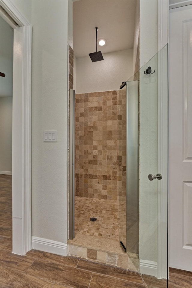 full bath with a walk in shower, baseboards, and wood finished floors