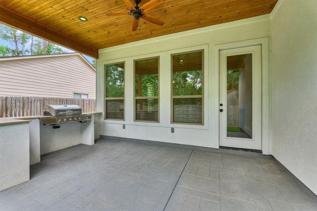 view of patio with an outdoor kitchen, ceiling fan, and fence