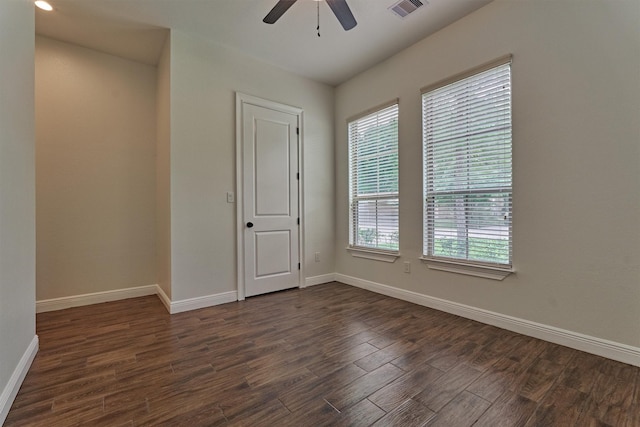 empty room with baseboards, ceiling fan, visible vents, and dark wood finished floors