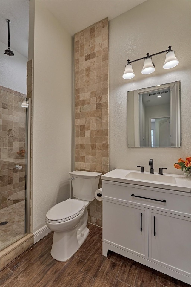 bathroom with vanity, a stall shower, toilet, and wood finished floors