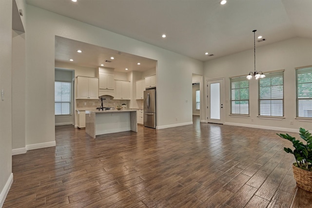 unfurnished living room featuring dark wood-type flooring, recessed lighting, plenty of natural light, and an inviting chandelier
