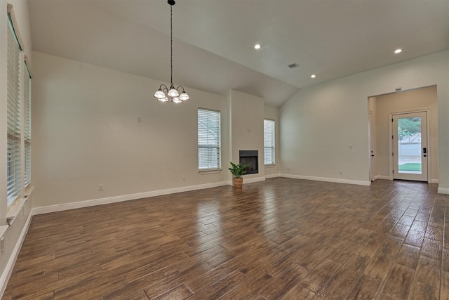 unfurnished living room with lofted ceiling, dark wood-style floors, recessed lighting, a fireplace with raised hearth, and a notable chandelier