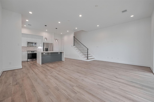 unfurnished living room with visible vents, recessed lighting, light wood-style floors, and stairway