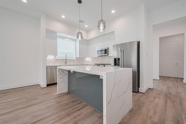 kitchen with appliances with stainless steel finishes, a center island, white cabinetry, visible vents, and modern cabinets