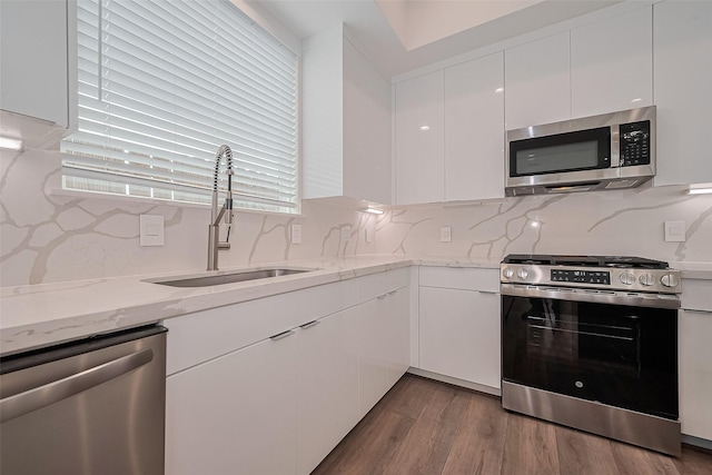 kitchen featuring white cabinets, backsplash, appliances with stainless steel finishes, and a sink