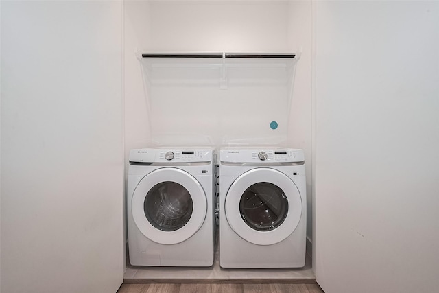 washroom featuring laundry area, washer and clothes dryer, and light wood-type flooring