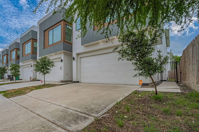 view of front of property with an attached garage, stucco siding, fence, and concrete driveway