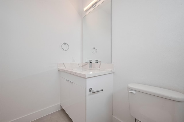 half bath featuring toilet, tile patterned floors, baseboards, and vanity