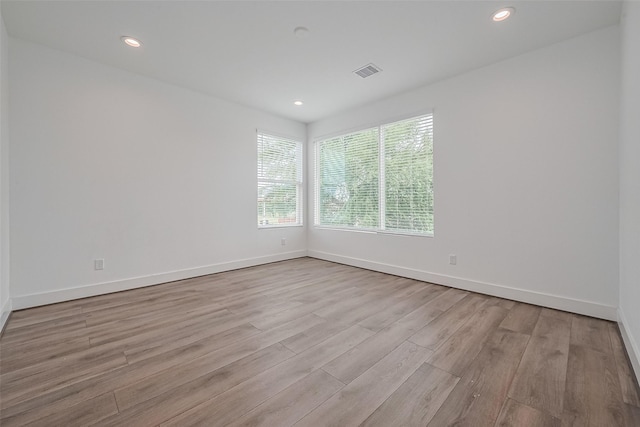empty room with visible vents, recessed lighting, baseboards, and wood finished floors