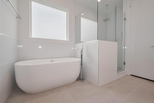 bathroom featuring tile patterned floors, a freestanding bath, and a shower stall