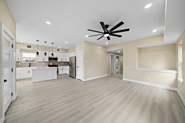 unfurnished living room featuring light wood-type flooring, a ceiling fan, baseboards, and recessed lighting