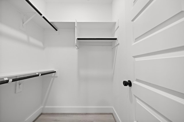 walk in closet with light wood-style floors