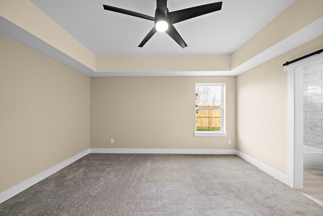 carpeted spare room featuring baseboards, ceiling fan, and a raised ceiling