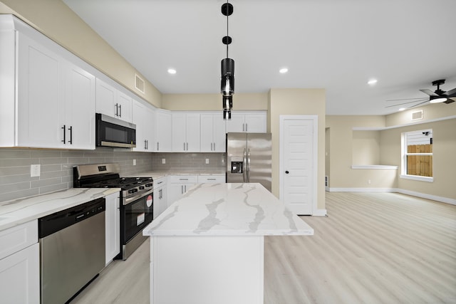 kitchen featuring visible vents, appliances with stainless steel finishes, a kitchen island, and tasteful backsplash