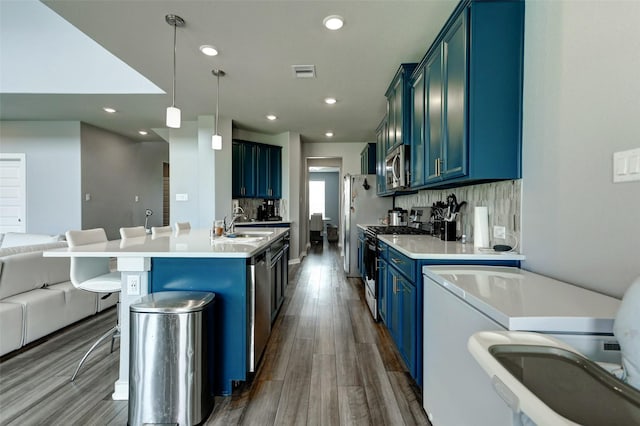 4910 Magnolia Springs Dr, Pearland, TX 77584 - kitchen featuring washer / dryer, open floor plan, dark wood-type flooring, blue cabinets, and appliances with stainless steel finishes