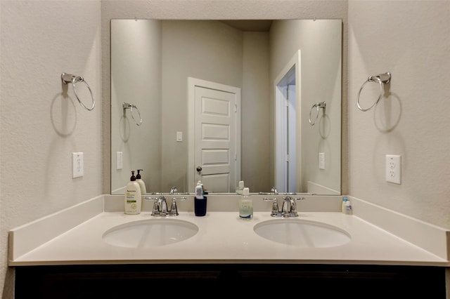 4910 Magnolia Springs Dr, Pearland, TX 77584 - bathroom featuring double vanity, a textured wall, and a sink
