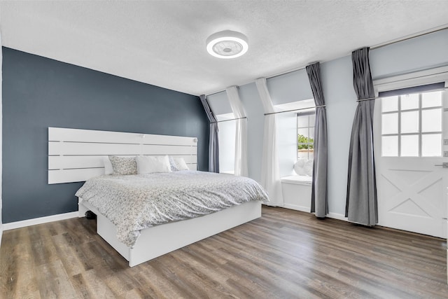 386 N Post Oak Ln, Houston, TX 77024 - bedroom featuring wood finished floors, a textured ceiling, and baseboards