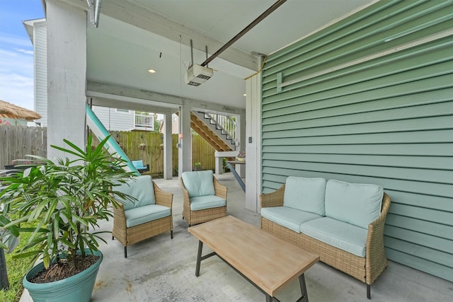 view of patio / terrace featuring outdoor lounge area, fence, and stairs