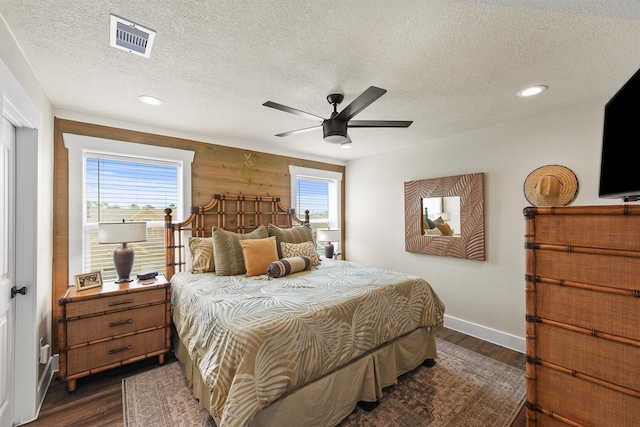 bedroom with visible vents, a textured ceiling, dark wood-style flooring, and baseboards