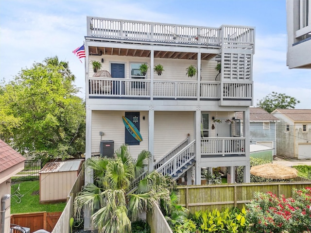 rear view of property with a storage unit, an outbuilding, fence private yard, and a balcony