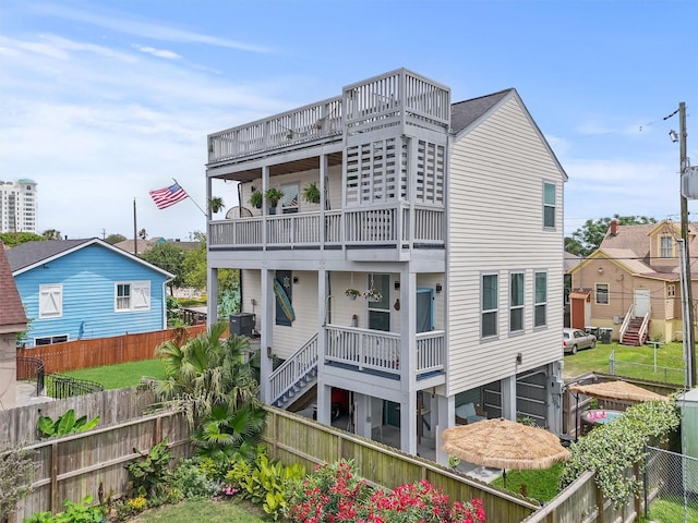 back of property with a fenced backyard, central air condition unit, and a balcony