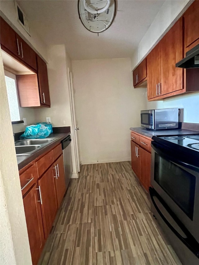 8100 Creekbend Dr Unit 117, Houston, TX 77071 - kitchen with appliances with stainless steel finishes, a sink, dark countertops, under cabinet range hood, and wood finished floors