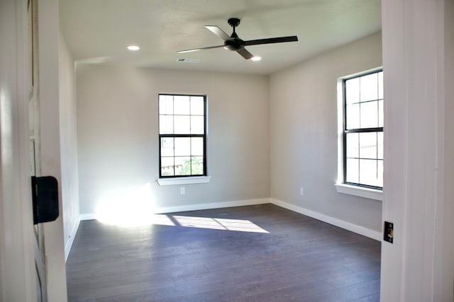 unfurnished room featuring baseboards, visible vents, dark wood-style floors, and a healthy amount of sunlight