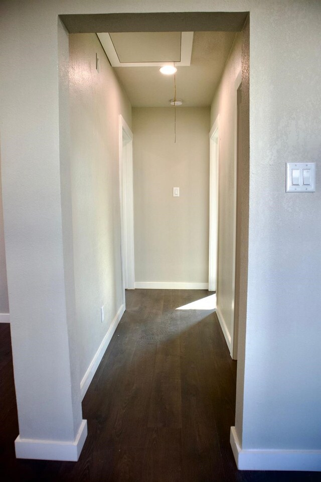 hallway featuring baseboards and dark wood-style floors