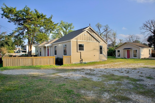 back of property featuring a lawn, fence, and board and batten siding