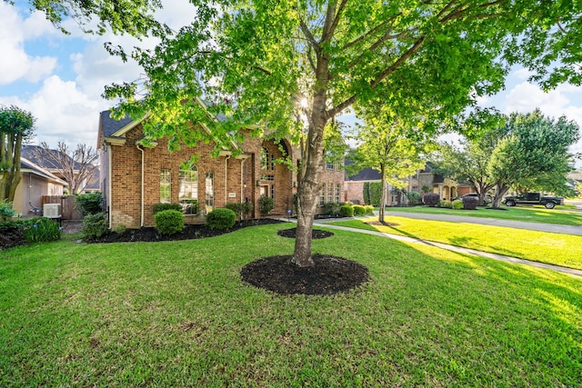 view of front of house with central air condition unit, brick siding, and a front lawn
